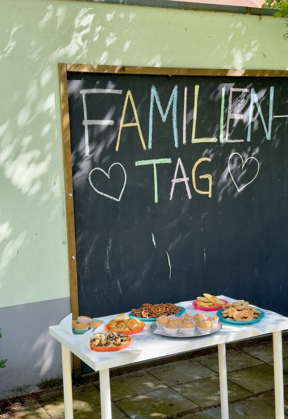 Tafel mit der Aufschrift Familientag und ein Tisch mit Gebäck im Außenbereich
